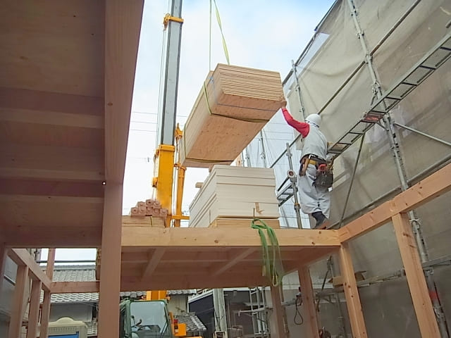 建設現場で木材を吊り上げるクレーン